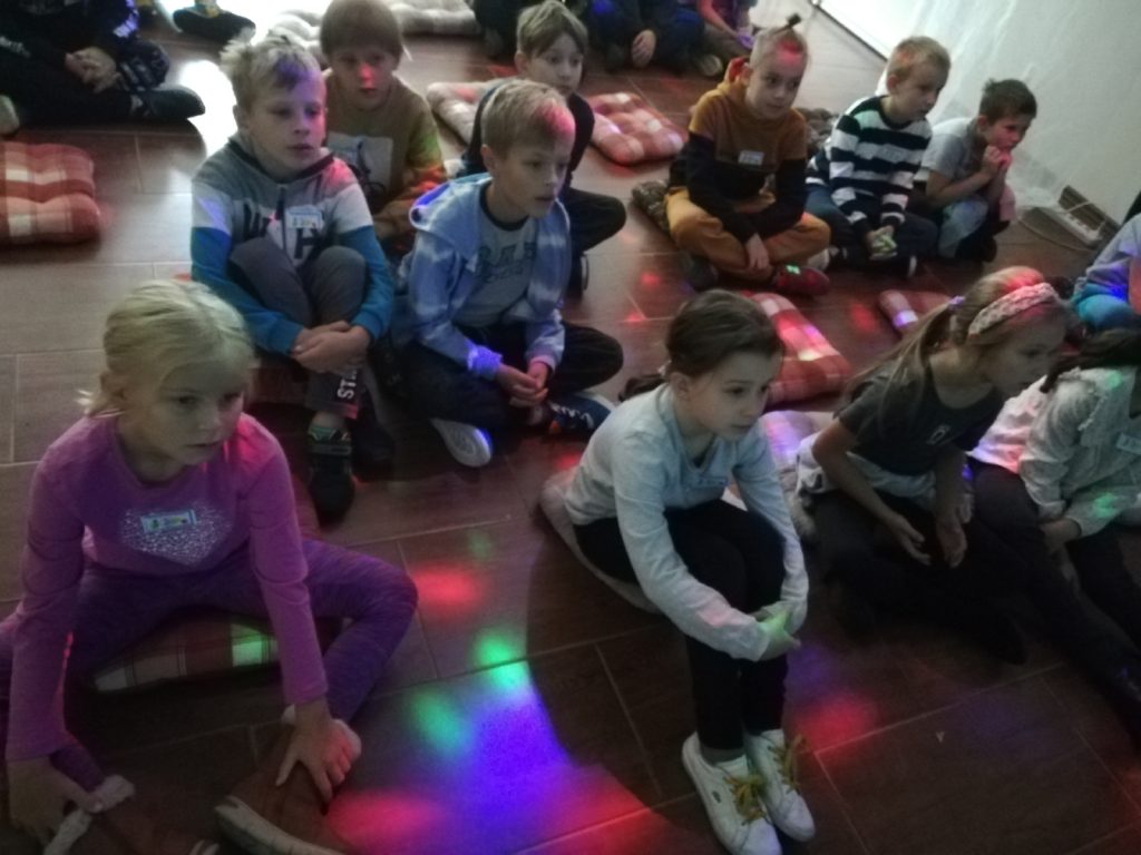 dzieci siedzące na kolorowej podłodze