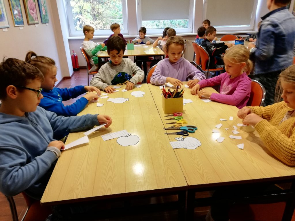 uczniowie przy stole wykonują prace plastyczne