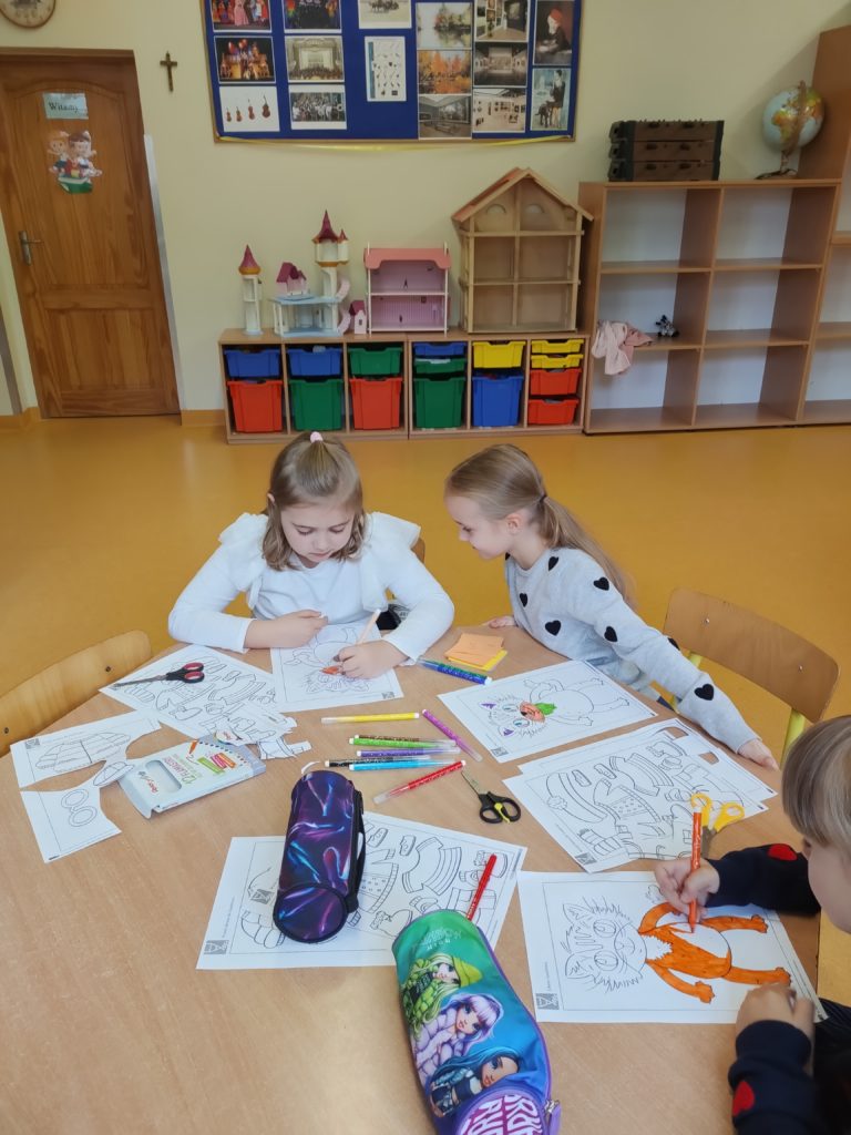 dzieci robią prace plastyczną przy stoliku