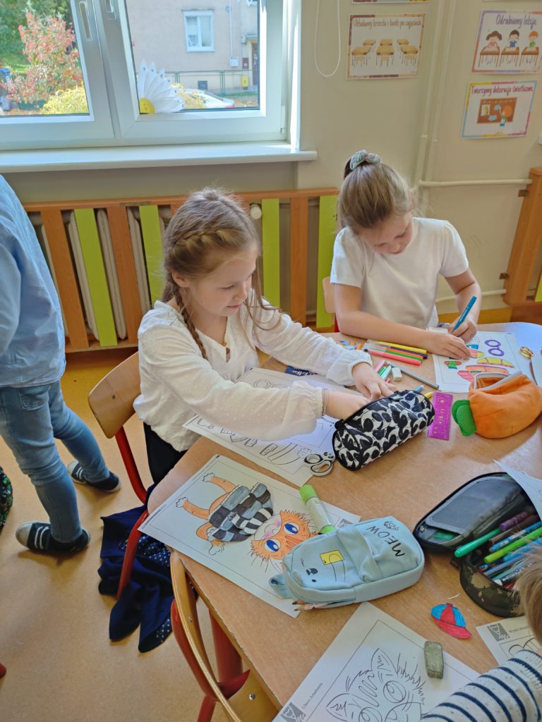 dzieci robią prace plastyczną przy stoliku