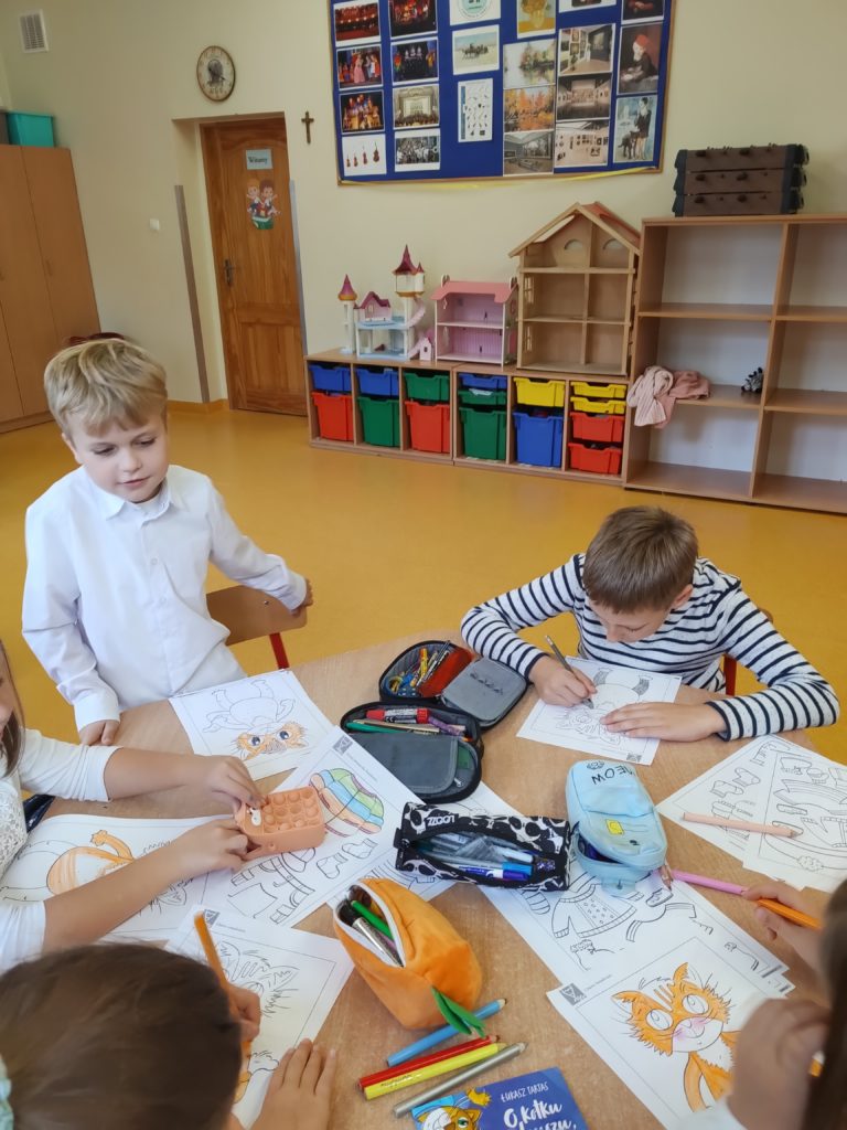 dzieci robią prace plastyczną przy stoliku