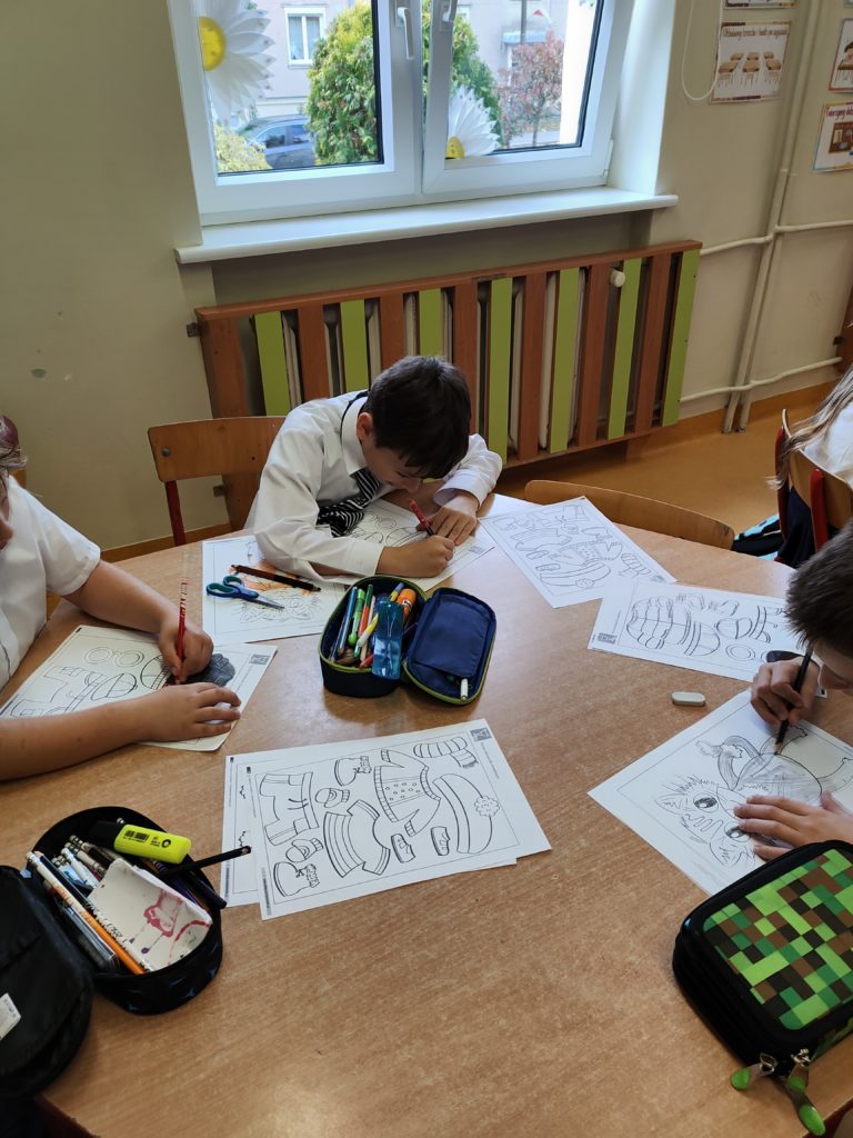 dzieci robią prace plastyczną przy stoliku