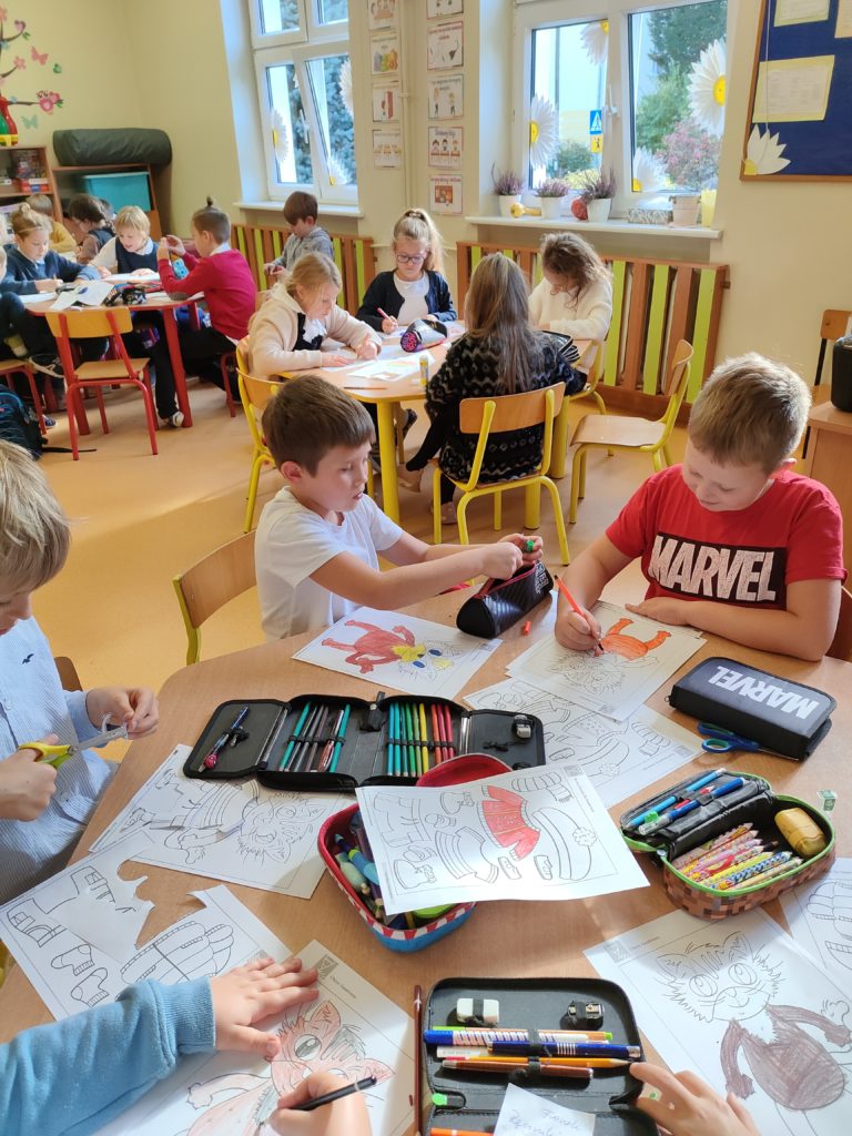 dzieci robią prace plastyczną przy stoliku