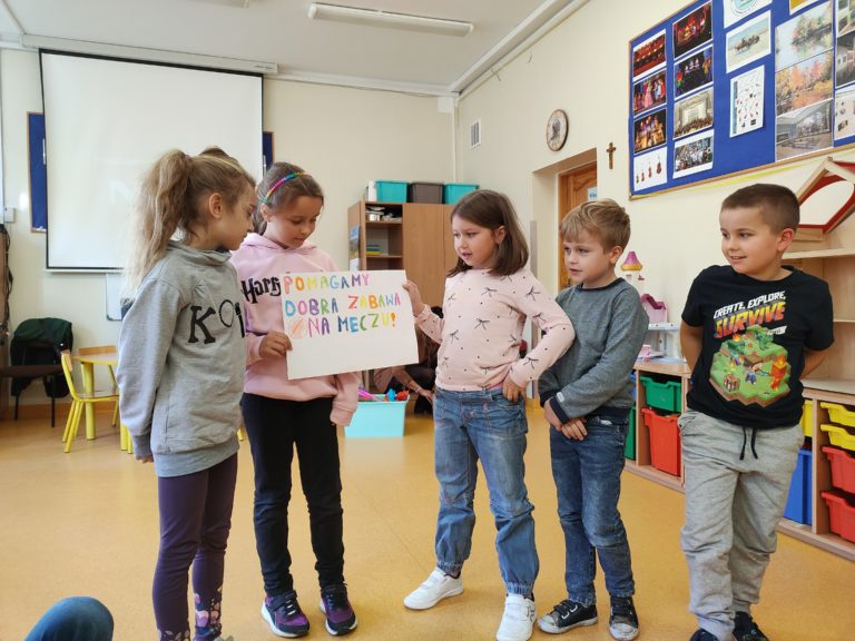 dzieci stojące, przedstawiające swoją grę planszową