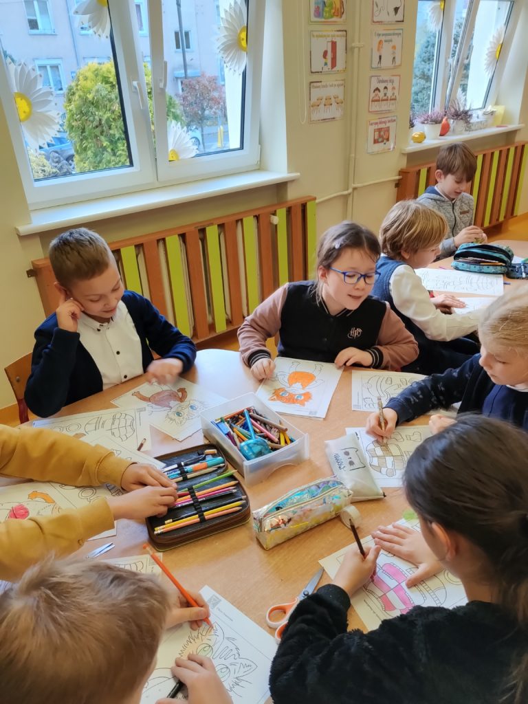 dzieci robią prace plastyczną przy stoliku