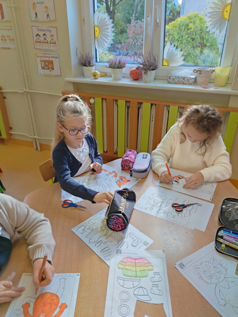 dzieci robią prace plastyczną przy stoliku