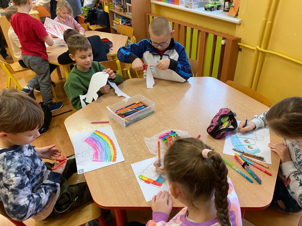 dzieci przy stoliku ozdabiają swoje opakowania na popcorn