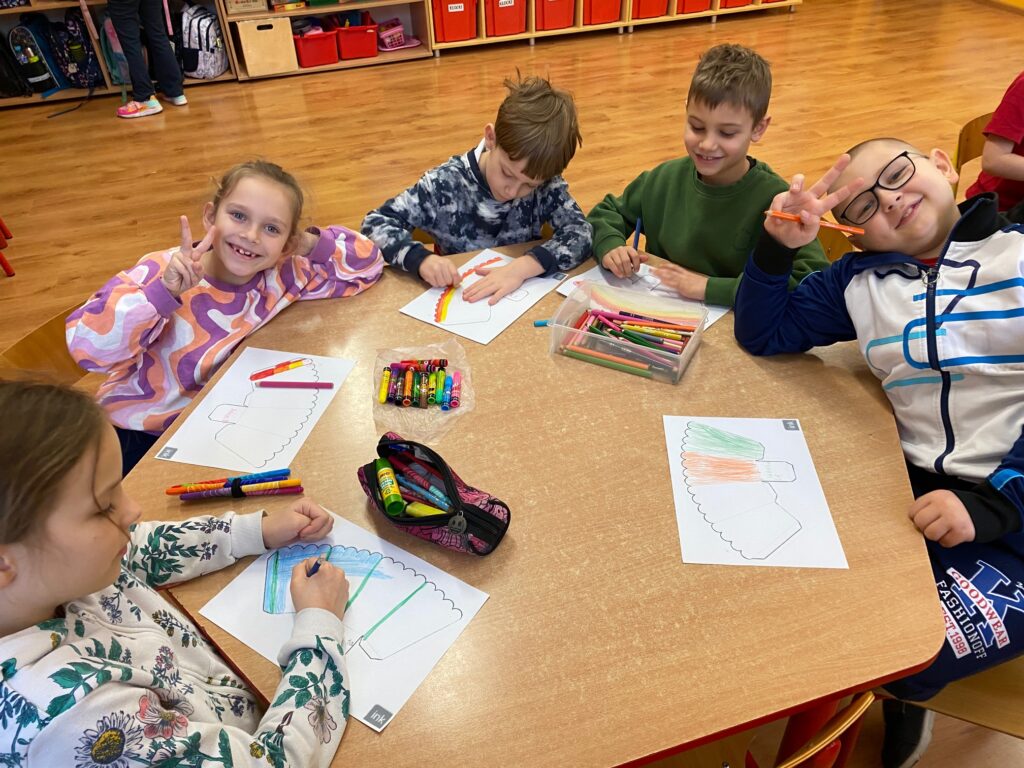 dzieci przy stoliku ozdabiają swoje opakowania na popcorn