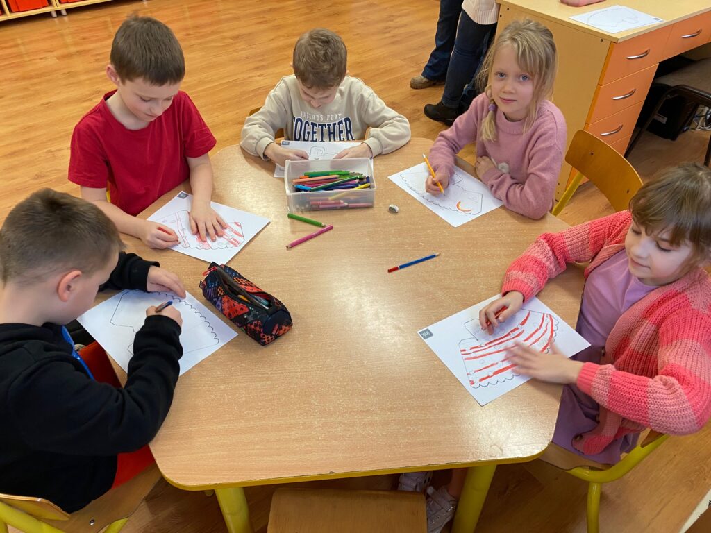 dzieci przy stoliku ozdabiają swoje opakowania na popcorn