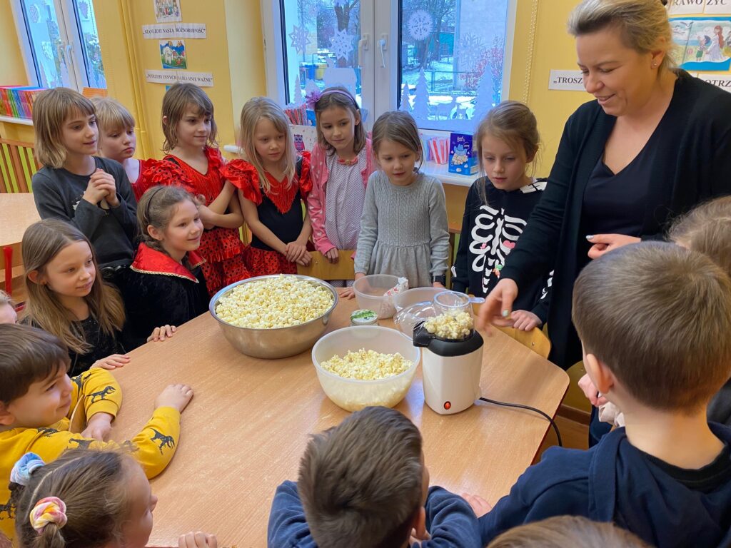 dzieci stoją przy misce z popcornenm