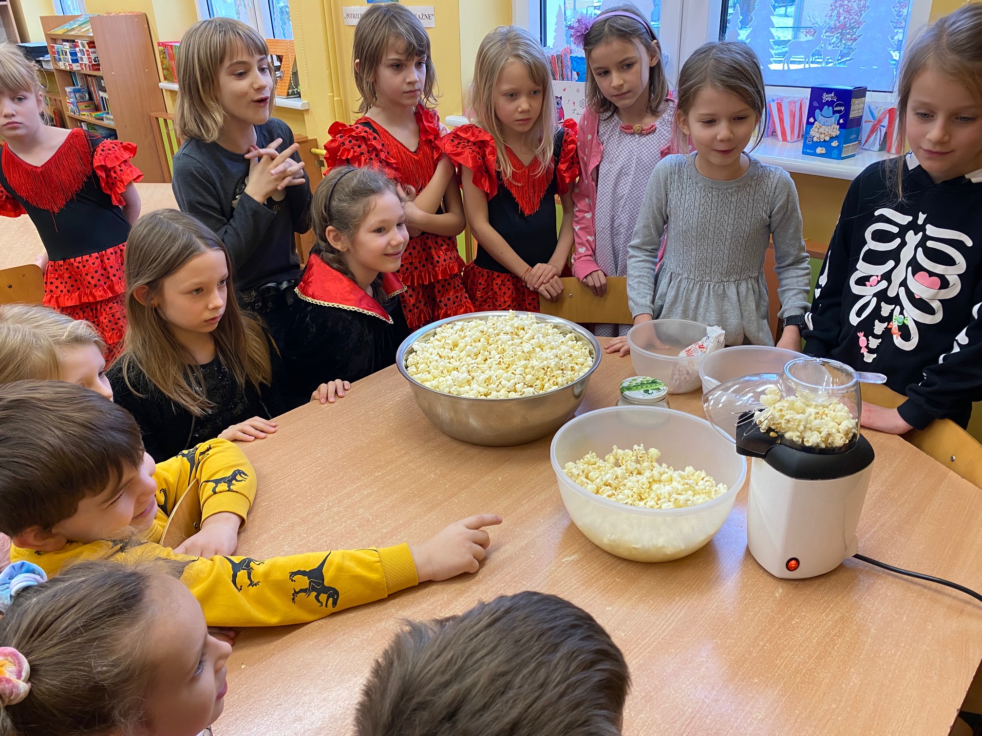 dzieci stoją przy misce z popcornenm