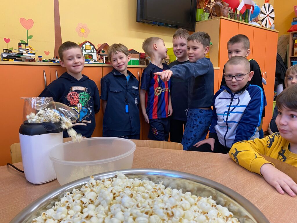 dzieci stoją przy misce z popcornenm