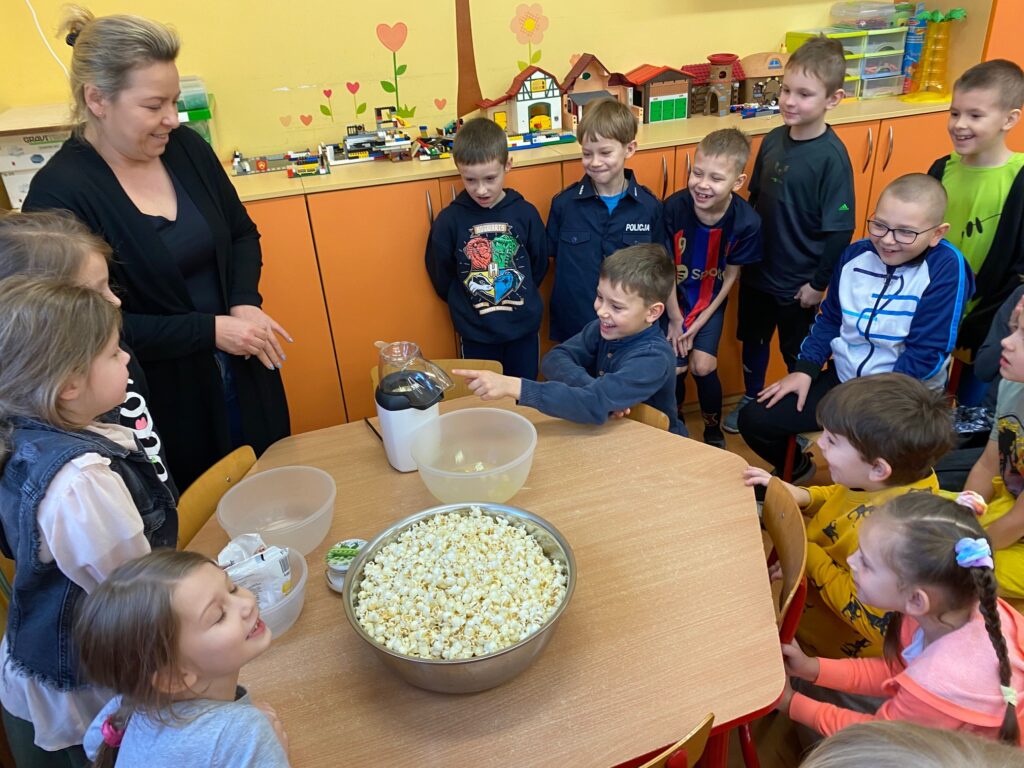 dzieci stoją przy misce z popcornenm