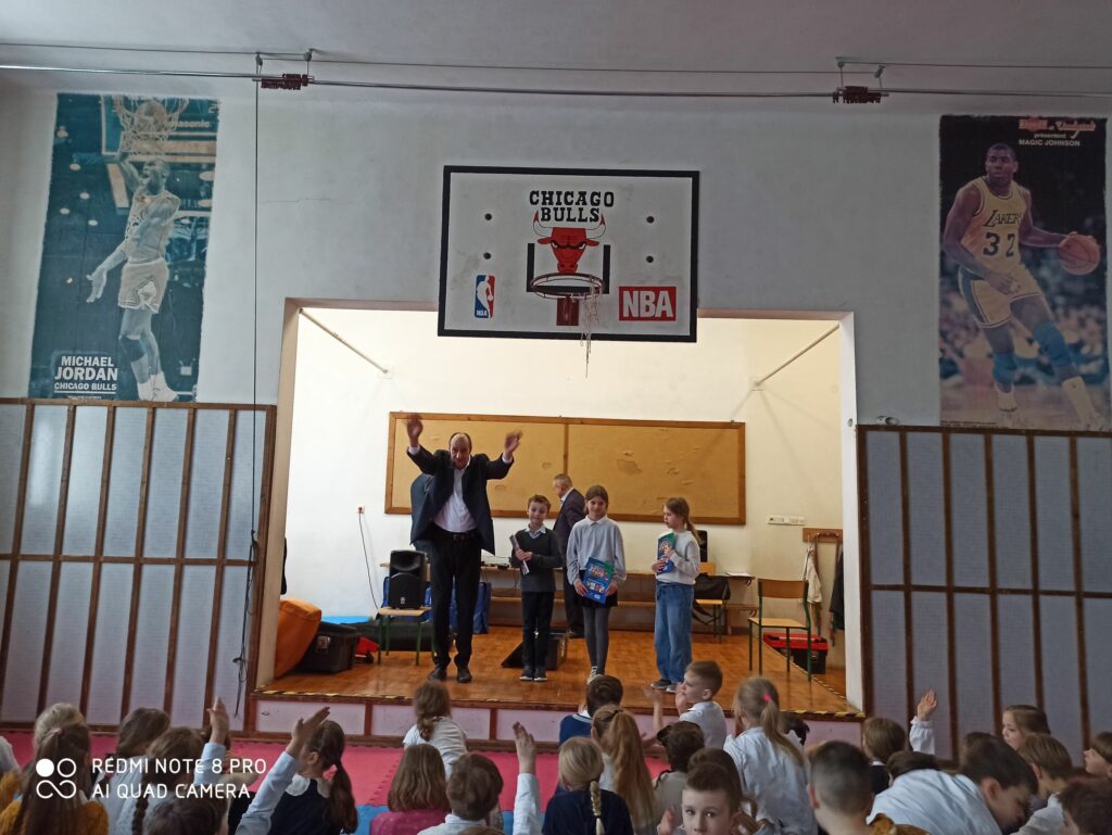 Zdjęcie przedstawia troje uczniów z nagrodami książkowymi. Są to zwycięzcy konkursu wiedzy.