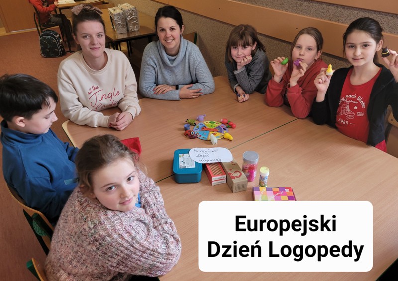 Na zdjęciu widać grupę dzieci siedzących przy wspólnym stole. Wszyscy są uśmiechnięci. Między nimi siedzą dwie ciemnowłose kobiety. Na stole leżą pomoce dydaktyczne do zajęć- kolorowe pudełka, koło fortuny, pojemniki.Zdjęcie opatrzone napisem "Europejski Dzień Logopedy"