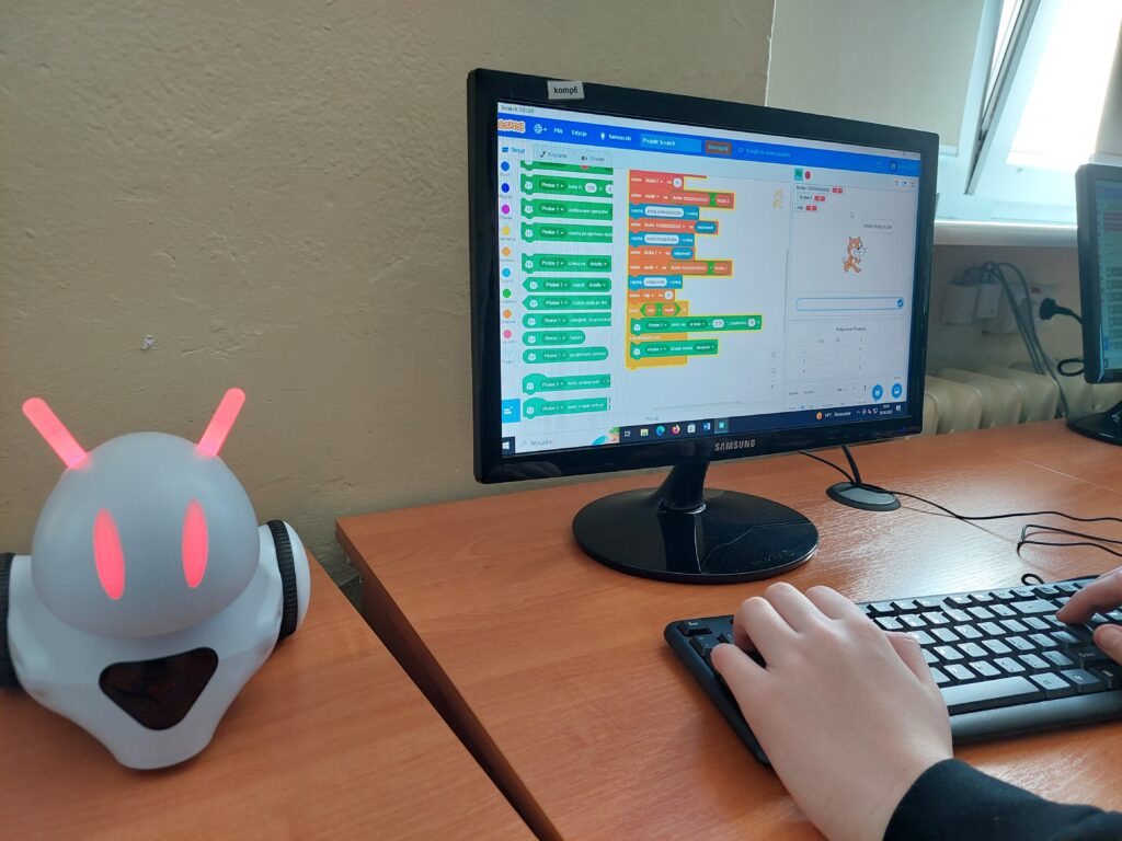 Robot i monitor z widocznym kodem.