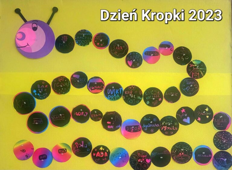 Z zdjęciu widać gąsienicę utworzoną z czarnych kół różnej wielkości. Każde koło zawiera pojedyncze imiona dzieci. Głowa gąsienicy jest utworzona z sześciu kół w odcieniach różu i fioletu. W prawym górnym rogu znajduje się napis „DZIEŃ KROPKI 2023”. Całość znajduje się na żółtym tle