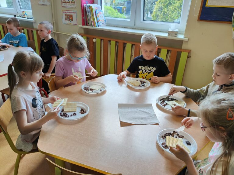 Dzieci siedzące przy stoliku, jedzące wafle posmarowane