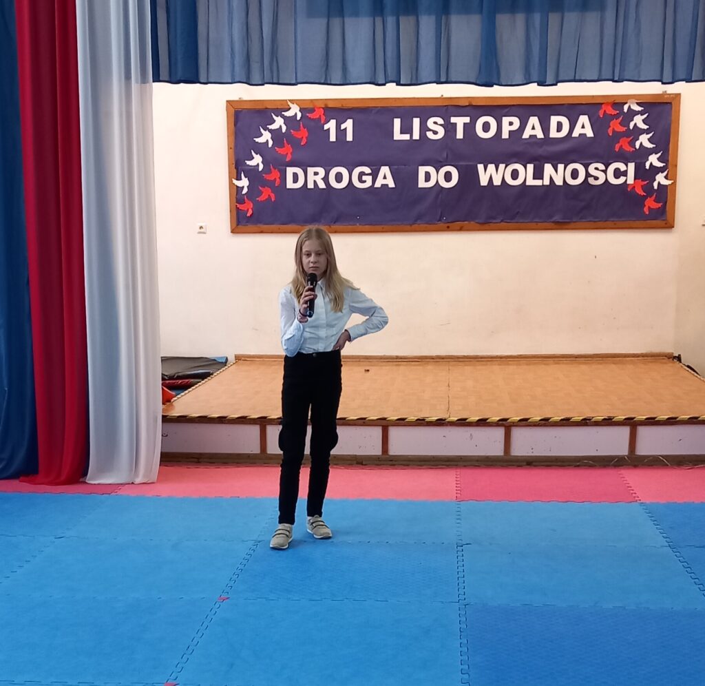 na rozświetlonej scenie dziewczynka solo wystąpiła, na środku sceny stoi i trzyma mikrofon