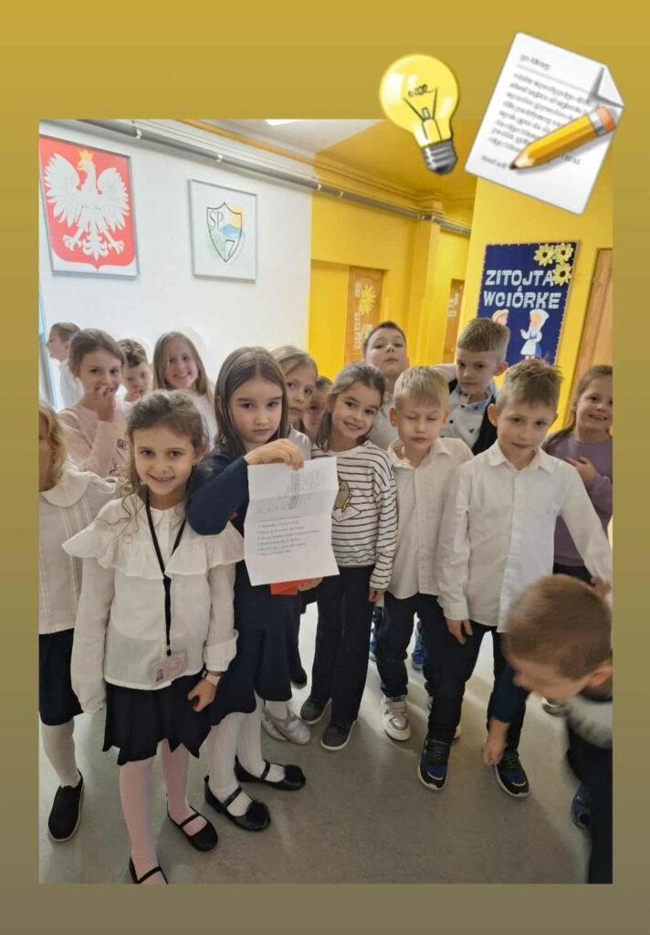 Zdjęcie przedstawia grupę dzieci z klasy 1c, uczestniczących w grze terenowej zorganizowanej z okazji Dnia Pluszowego Misia. Dzieci stoją na szkolnym korytarzu, a jedna z dziewczynek trzyma kartkę z zadaniami, które były częścią zabawy. W tle widać godło Polski, herb szkoły oraz dekorację z napisem „Zitujęta Wciórkę”. Wszystkie dzieci są odświętnie ubrane, co podkreśla wyjątkowość wydarzenia. Ich zaangażowanie i uśmiechy wskazują na dobrą zabawę i entuzjazm związany z poszukiwaniem ukrytego misia.