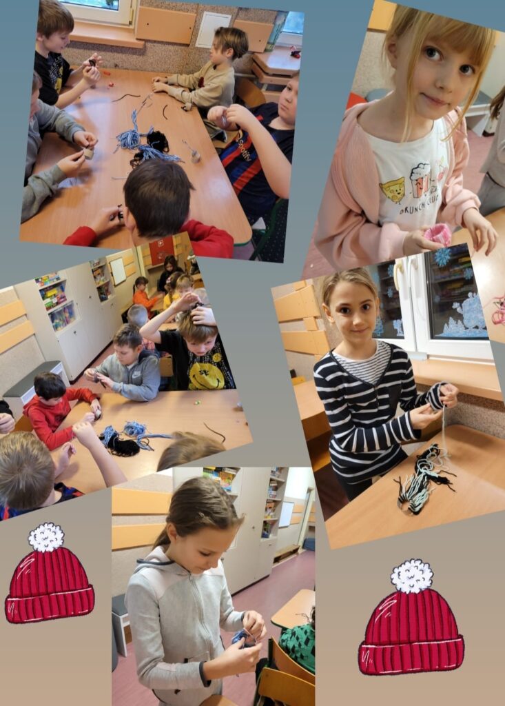 Na zdjęciu widzimy dzieci pracujące przy stolikach w klasie. Grupa uczniów zajmuje się rękodziełem, prawdopodobnie wykonując czapki z włóczki lub inne prace manualne. W tle widać elementy wyposażenia sali, takie jak półki z materiałami edukacyjnymi. Niektóre dzieci są skupione na pracy, inne prezentują swoje efekty. W lewym dolnym rogu i prawym górnym rogu dodano grafiki przedstawiające czerwone zimowe czapki z pomponami.