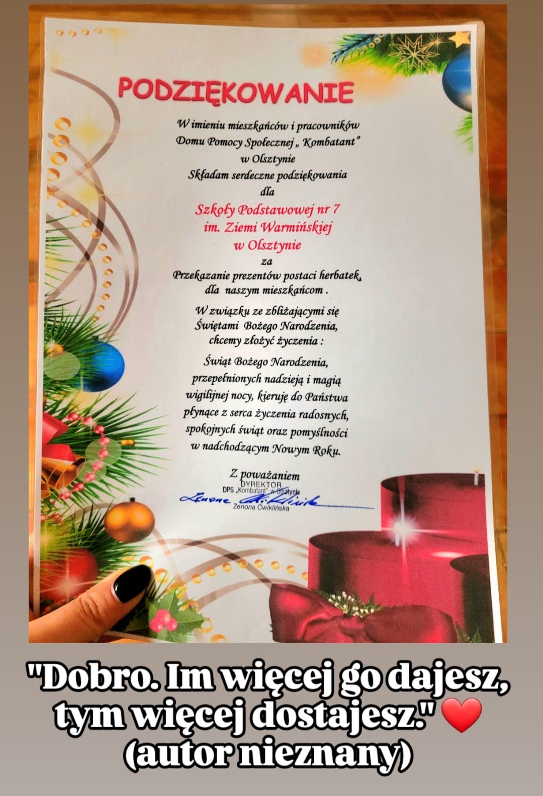 Na zdjęciu znajduje się dyplom z podziękowaniem zatytułowany "PODZIĘKOWANIE", wystosowany przez Dom Pomocy Społecznej „Kombatant” w Olsztynie. Treść podziękowania skierowana jest do Szkoły Podstawowej nr 7 im. Ziemi Warmińskiej w Olsztynie za przekazanie prezentów w postaci herbat i kaw dla mieszkańców domu pomocy. Na dole dyplomu widnieją życzenia świąteczne, w których czytamy: „Świąt Bożego Narodzenia, przepełnionych nadzieją i magią wigilijnej nocy, kieruję do Państwa płynące z serca życzenia radosnych, spokojnych świąt oraz pomyślności w nadchodzącym Nowym Roku.” Podpisano: Dyrektor DPS „Kombatant” w Olsztynie, Zenona Ćwiklińska. Pod dyplomem znajduje się cytat: „Dobro. Im więcej go dajesz, tym więcej dostajesz.” (autor nieznany) obok czerwonego serca.
