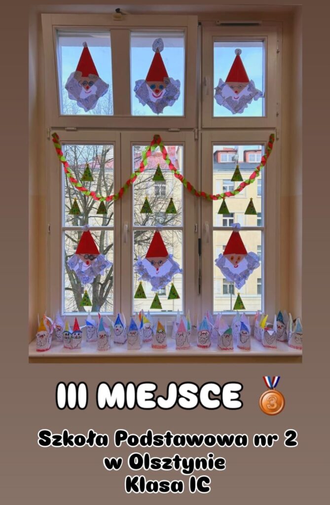 Zdjęcie przedstawia świąteczną dekorację okienną wykonaną przez uczniów klasy 1C Szkoły Podstawowej nr 2 w Olsztynie. Na szybach widoczne są rysunki przedstawiające twarze Mikołajów z charakterystycznymi czerwonymi czapkami i brodami, a także papierowe choinki. Dodatkową ozdobą jest łańcuch z papieru, w kolorach zielonym i czerwonym, zawieszony wzdłuż okna. Na parapecie ustawiono ręcznie wykonane prace plastyczne – papierowe figurki z rysunkami Mikołajów. Pod zdjęciem widnieje napis informujący o zdobyciu III miejsca w konkursie przez klasę 1C. Całość ma radosny, świąteczny charakter.