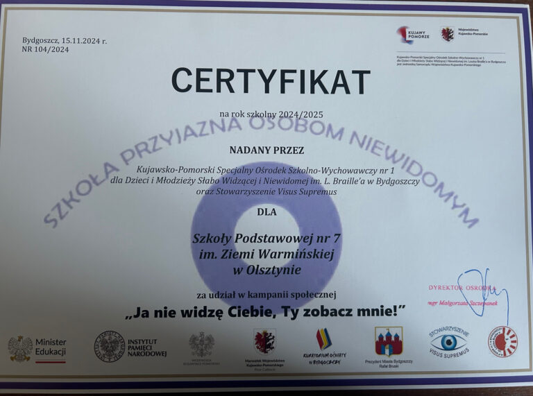 Zdjęcie przedstawia certyfikat przyznany Szkole Podstawowej nr 7 im. Ziemi Warmińskiej w Olsztynie na rok szkolny 2024/2025. Certyfikat nosi tytuł "Szkoła Przyjazna Osobom Niewidomym" i został nadany przez Kujawsko-Pomorski Specjalny Ośrodek Szkolno-Wychowawczy nr 1 dla Dzieci i Młodzieży Słabo Widzącej i Niewidomej im. L. Braille’a w Bydgoszczy oraz Stowarzyszenie Visus Supremus. Certyfikat przyznano za udział w kampanii społecznej "Ja nie widzę Ciebie, Ty zobacz mnie!". Dokument został podpisany przez dyrektora ośrodka i zawiera kilka oficjalnych logotypów, w tym Ministerstwa Edukacji, Instytutu Pamięci Narodowej, a także innych organizacji zaangażowanych w inicjatywę. Tło certyfikatu jest jasne, a napisy i grafiki są w odcieniach fioletu, czerni i czerwieni. W lewym górnym rogu znajdują się oficjalne pieczęcie i logotypy organizatorów.