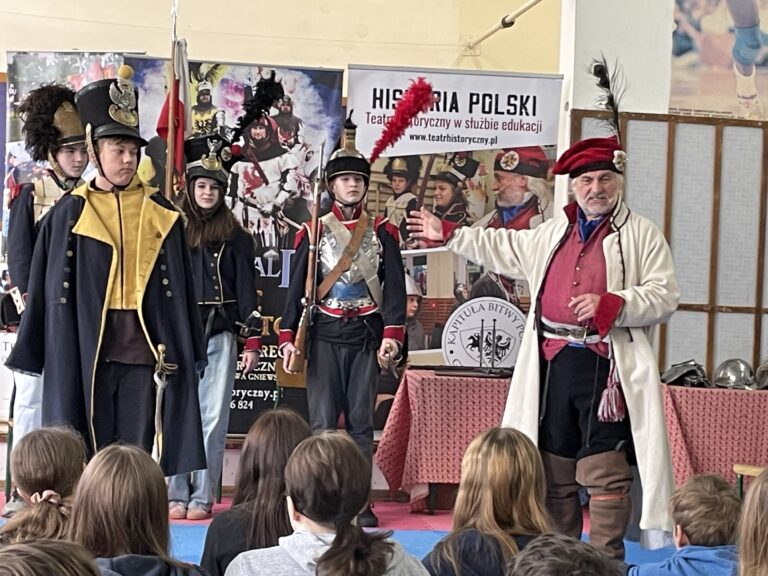 Stoi czworo uczniów w mundurach z pierwszej połowy XIX wieku.