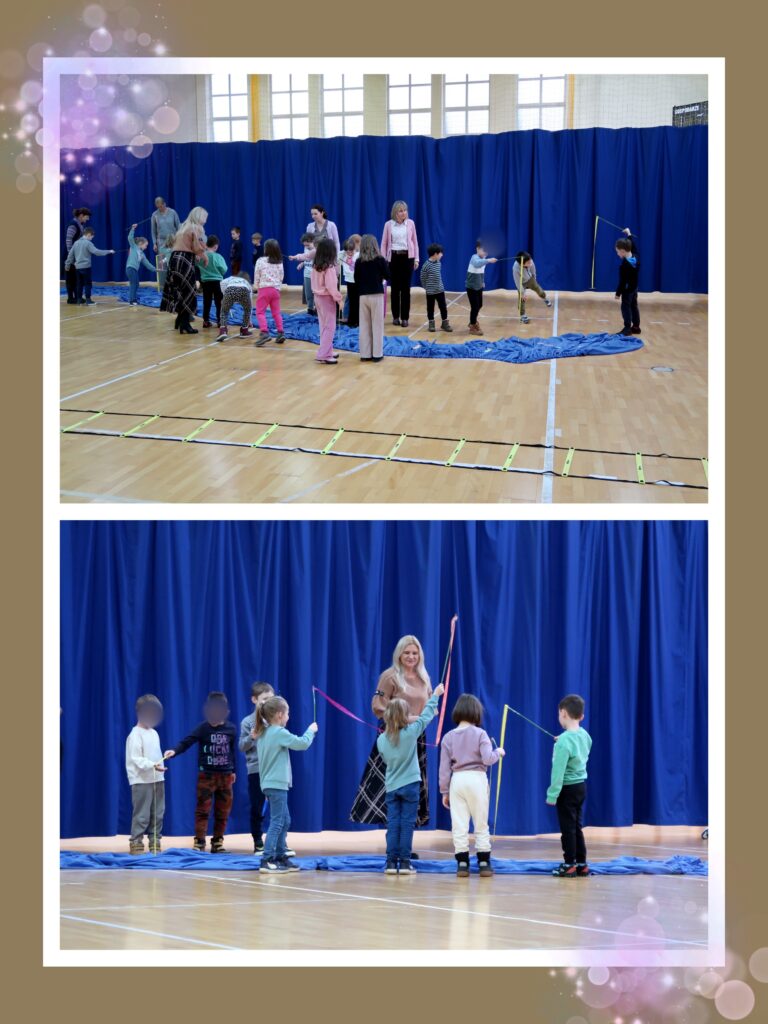 Na tych zdjęciach widzimy dzieci uczestniczące w zabawach ruchowych na sali gimnastycznej. Dzieci ustawione w grupach biorą udział w aktywności z długą liną i materiałem rozłożonym na podłodze, który przypomina rzekę. Towarzyszą im dorośli, którzy pomagają w organizacji zabawy. Całość odbywa się na tle niebieskiej kurtyny, a w tle widać wysokie okna wpuszczające dużo światła. Drugie zdjęcie: Dzieci trzymają kolorowe wstążki, a jedna z dorosłych osób (blondynka w eleganckiej spódnicy) prowadzi zabawę. Maluchy wyglądają na zaangażowane i skoncentrowane. Zabawa polega na łowieniu rybek. Zdjęci są oprawione w elegancką, złotobrązową ramkę z efektem świetlistych bąbelków, co nadaje im ciepły, bajkowy charakter.