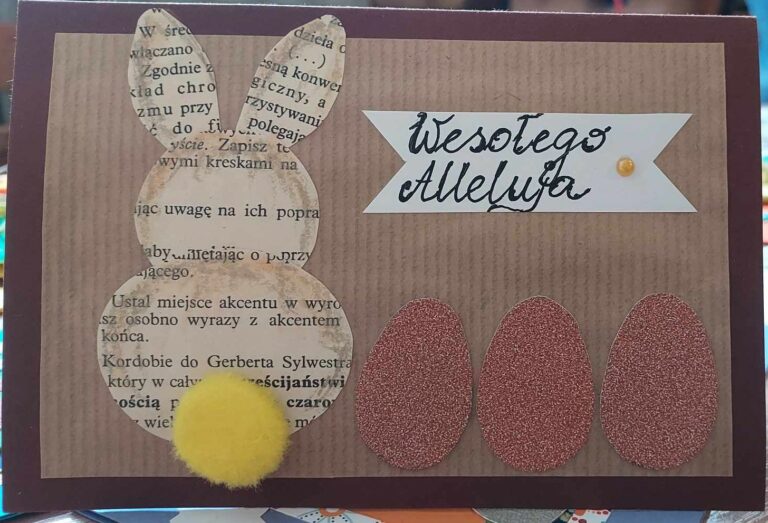 Zdjęcie przedstawia kartke świąteczną z napisem Wesołego Alleluja zająca ustawionego tyłem z widocznym żółtym ogonkiem oraz trzy jajka papierowe