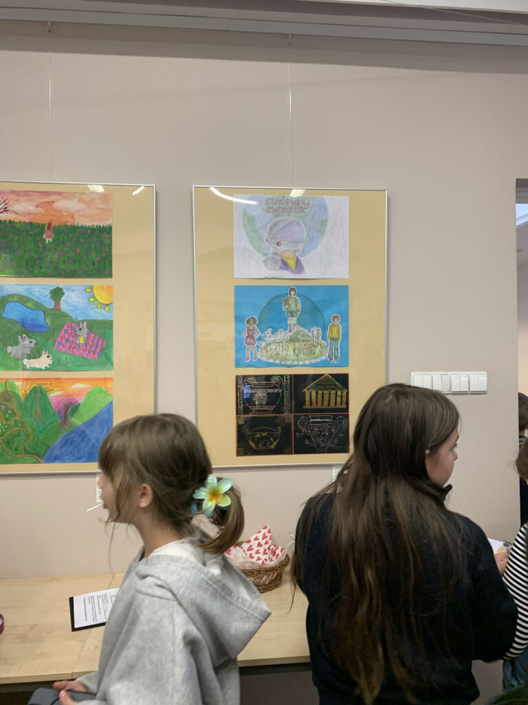 na ścianie wiszą dwie prostokątne antyramy. W każdej z nich na żółtym tle umieszczone są po 3 prace dzieci.