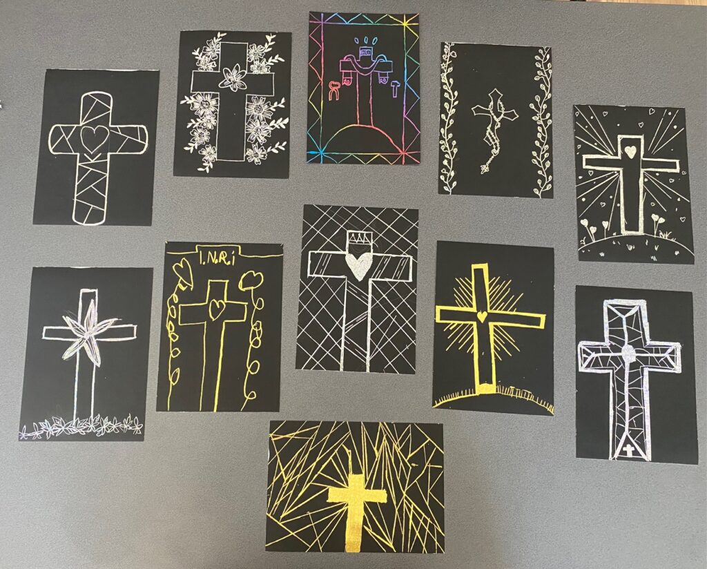 Zdjęcie przedstawia prace plastyczne. Rysunek krzyża w różnych kolorach wydrapanego z czarnego tł