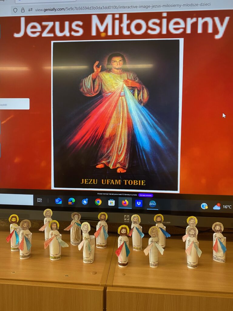 Zdjęcie przedstawia figurki Jezusa zrobione z plasteliny ustawione przed ekrane na którym wyświetlono plakat z Jezusem Miłosiernym