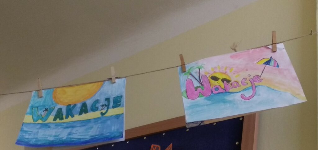 Zdjęcie przedstawia prace uczniów, które przedstawiają, krótkie napisy-wakacje i rysunki tematycznie z nimi związane wodę, piasek, słońce.