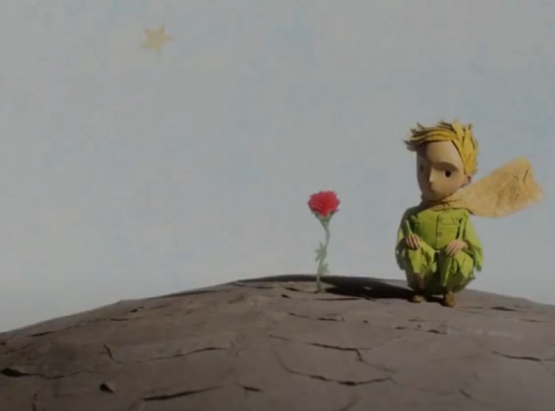 Kadr z filmu "Mały Książę". Na zdjęciu Mały Książę siedzący obok czerwonej Róży.